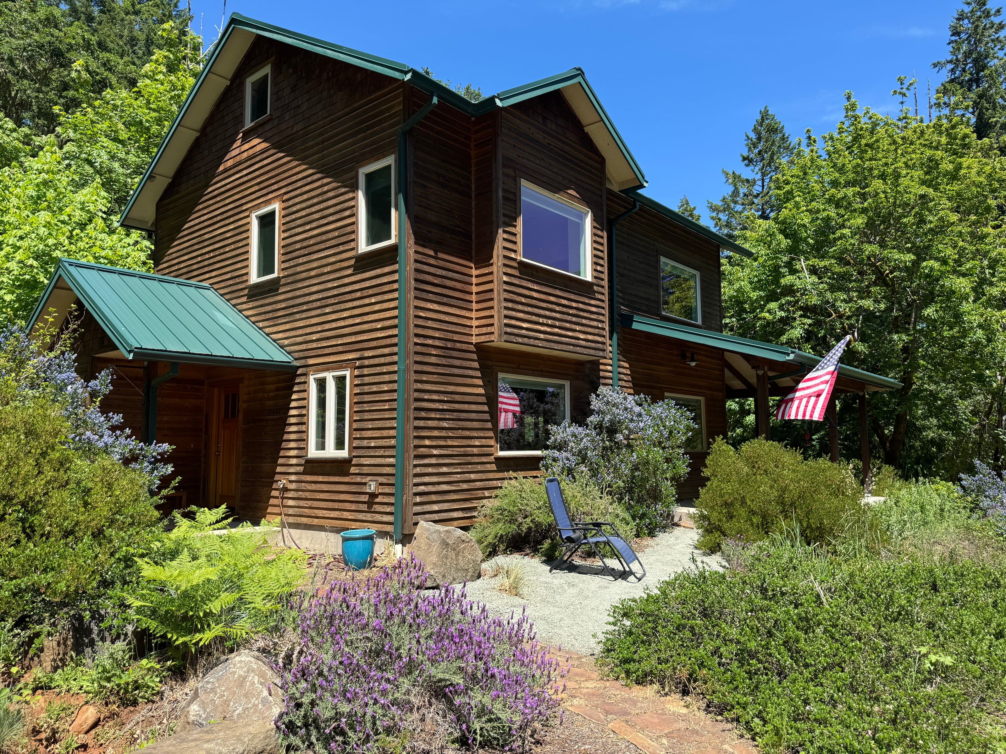 Corner view of the wrap porch in late spring, lavender and gravel path in the foreground