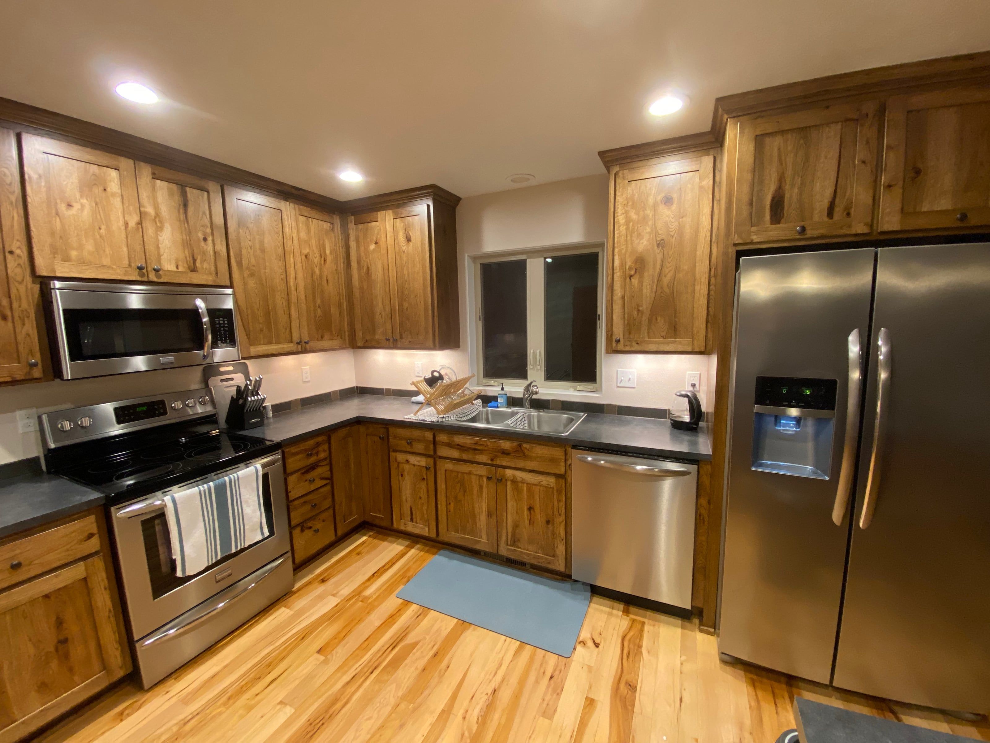Kitchen with rustic hickory cabinets, slate-dark counters, and stainless appliances