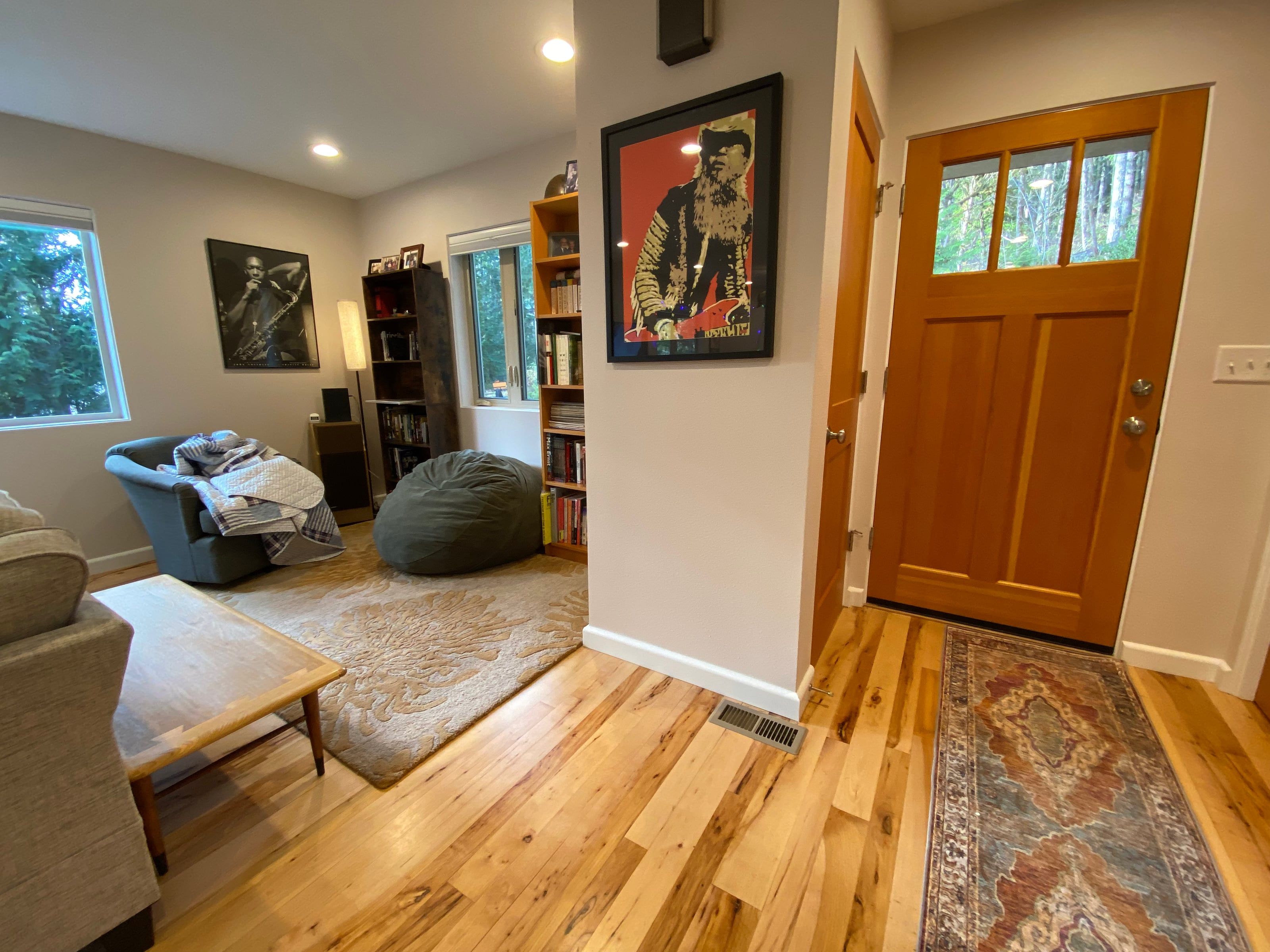 Living room and entry — light hickory floors, craftsman door with glass lites, art on warm gray walls
